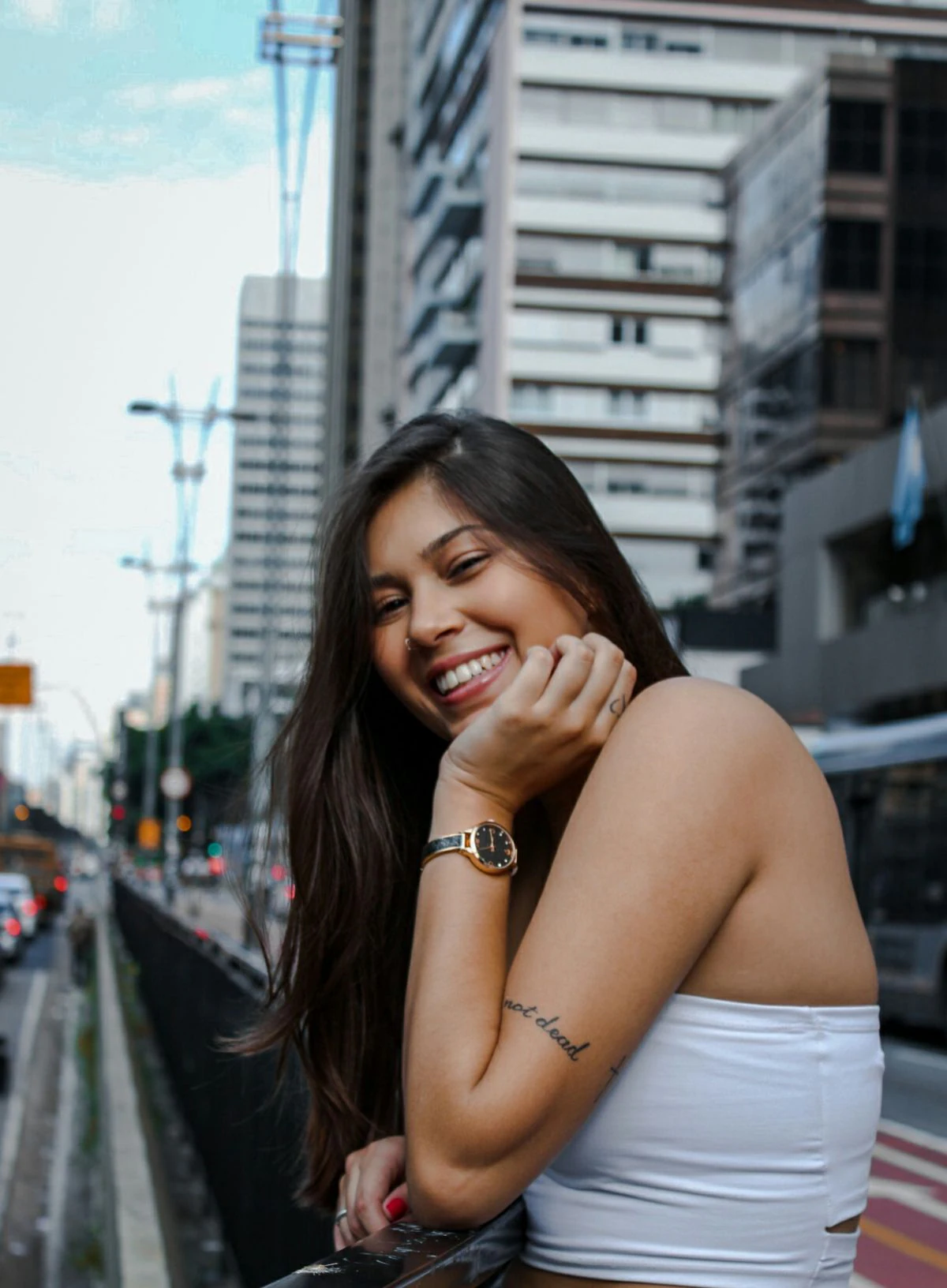 Mulher jovem sorrindo para a câmera em uma avenida de São Paulo