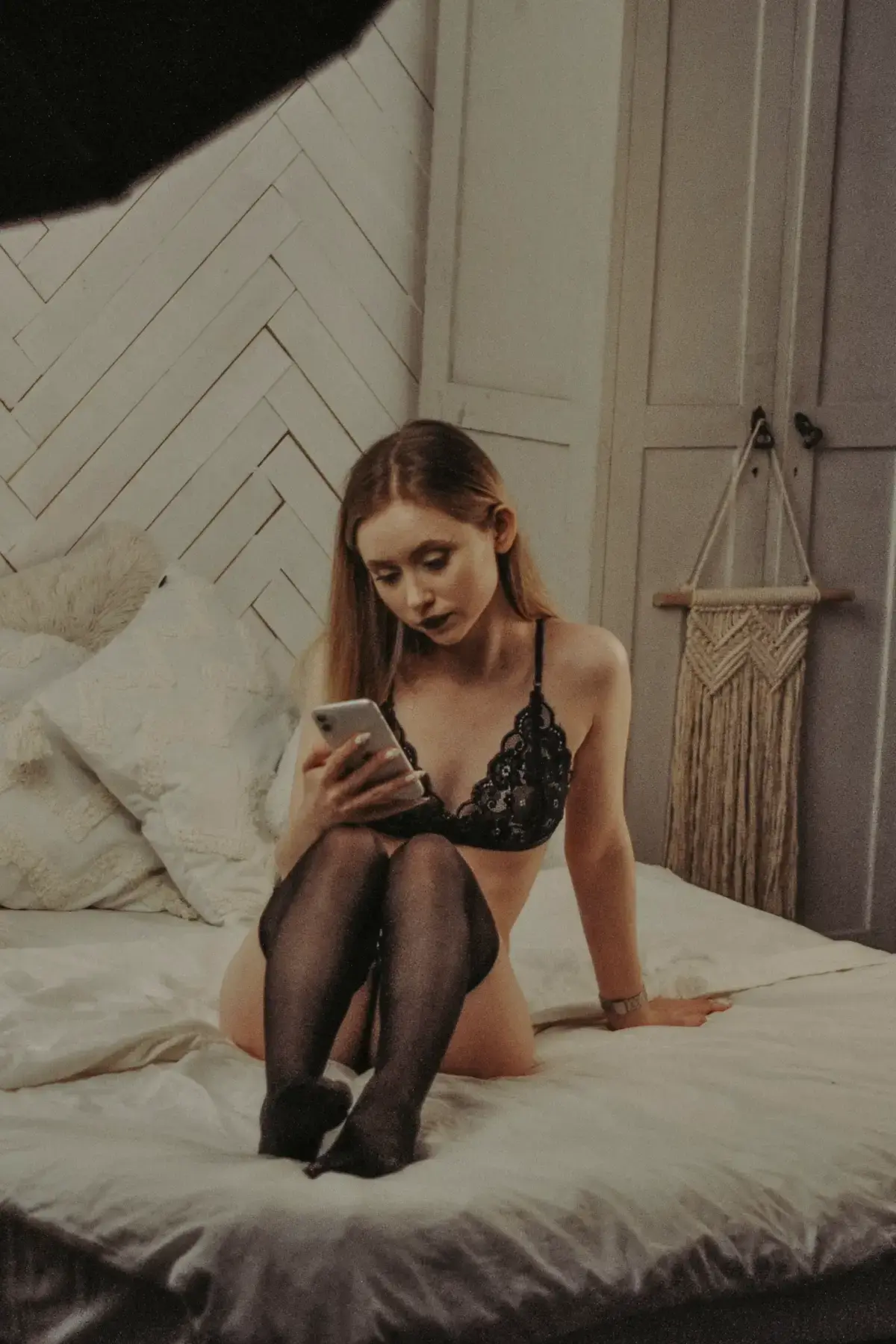 Woman in lingerie on a bed looking at her phone