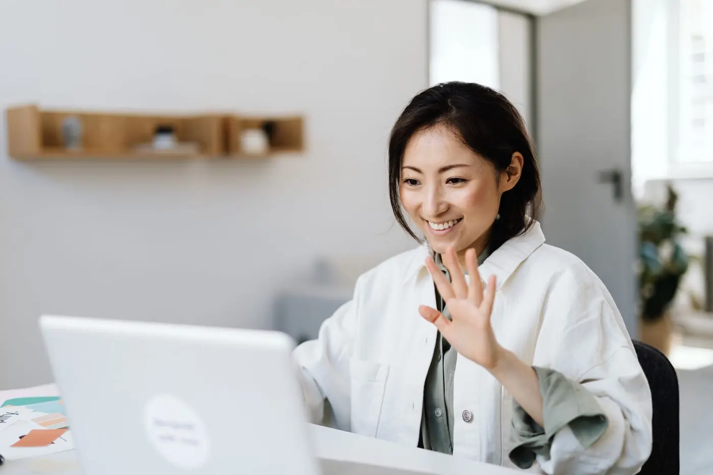 Smiling woman waving at her laptop on a video call
